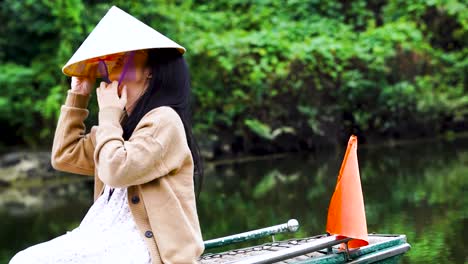 Turista-Vietnamita-Poniéndose-Un-Sombrero-Cónico-En-Un-Barco-En-Ninh-Binh