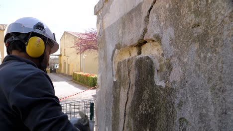 Slowmotion-shot-of-a-construction-worker-throwing-cement-into-a-large-crack-in-the-wall