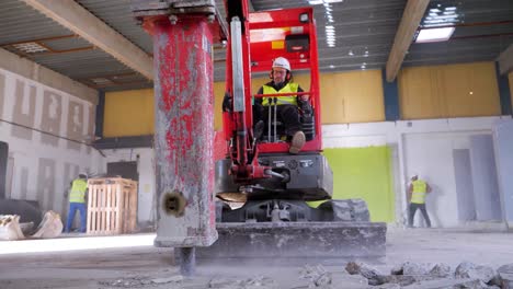 Male-using-his-excavator-drill-machine-to-open-the-floor-up-in-an-indoor-construction-site