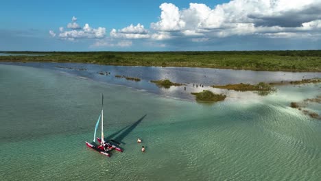 Luftbild-Rund-Um-Ein-Kleines-Segelboot,-Das-Im-Warmen,-Transparenten-Wasser-Der-Bacalar-Lagune-Verankert-Ist,-Im-Sonnigen-Mexiko---Umlaufbahn,-Drohnenaufnahme