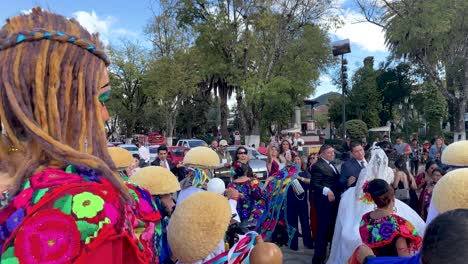 slow-motion-shot-of-a-wedding-couple-surrounded-by-traditional-dancers-in-san-cristobal-de-las-casas,-chiapas,-mexico