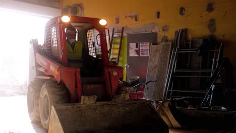 Hombre-Conduciendo-Hacia-El-Interior-Del-Edificio-Usando-Su-Máquina-Bob-Cat