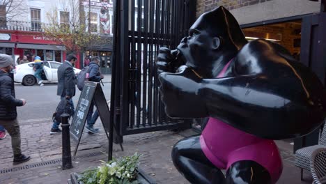 Primer-Plano-De-Hombres-Y-Mujeres-Locales-Entrando-En-El-País-De-Las-Maravillas-Del-Invierno-En-Londres,-Reino-Unido,-Con-Una-Estatua-De-Gorila-Negro-A-Lo-Largo-Del-Costado-Durante-El-Día