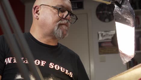 Tattoo-artist-with-piercing-in-his-nose-being-very-concentrated-while-tattooing