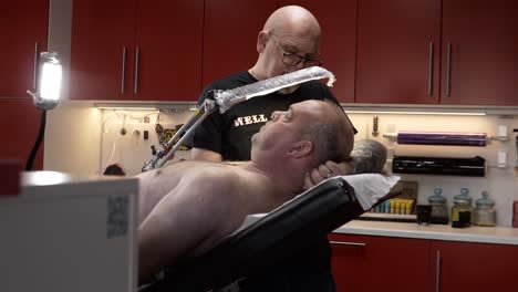 Tattoo-artist-in-his-studio-tattooing-his-clients-arm-and-being-very-focussed