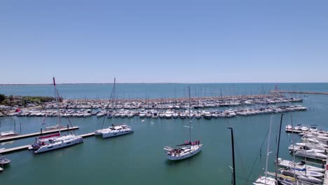 Aerial-view-over-the-marina-of-Montpellier,-in-southern-France,-while-a-sail-boat-is-motoring-n-to-the-mediterranean-sea