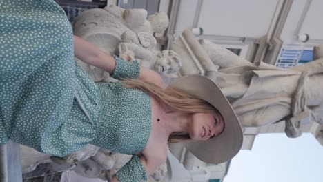 Beautiful-Young-Woman-Tourist-In-Summer-Dress-And-A-Hat-Sitting-In-Front-Of-A-Water-Fountain-With-Statue-Of-Saint-Andrew-At-The-Centre-Of-Piazza-Duomo,-Campania,-Amalfi,-Italy