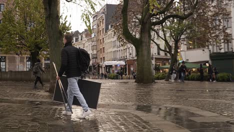 Man-walking-around-the-grasmarkt-in-brussels-with-billiard-equipment