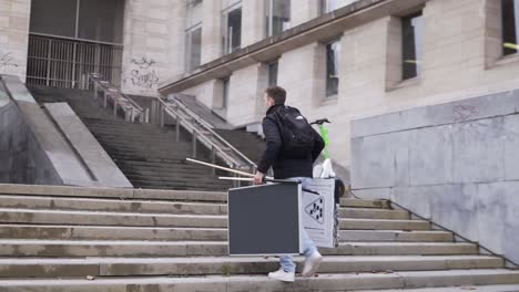 Man-walking-up-the-stairs-of-Kunstberg,-Brussels,-carrying-a-billiard-set-to-play-on-the-streets-against-strangers