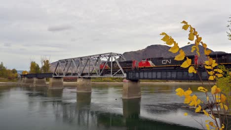 Un-Tren-De-Carga-Que-Cruza-El-Río-South-Thompson-A-Través-Del-Puente-Cnr-Cerca-Del-Parque-Ribereño-Al-Este-Del-Centro-De-Kamloops-En-Un-Día-Nublado-En-Otoño