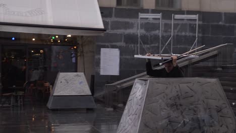 Man-with-a-table-on-his-head-running-for-shelter-from-the-rain-in-Monts-des-Arts-in-Brussels,-Belgium