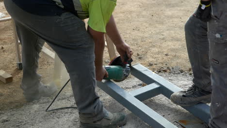 Trabajadores-De-La-Construcción-Que-Cortan-El-Marco-De-Acero-Usando-Una-Sierra-De-Disco-Que-Hace-Chispas-Que-Fabrican-Un-Módulo-De-Vivienda