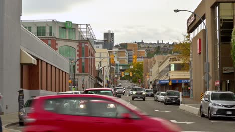 In-downtown-Kamloops-on-a-grey-day-in-the-fall,-cars-and-pedestrians-move-down-3rd-Avenue-and-Lansdowne-Street