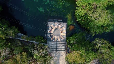 Vista-Aérea-De-Arriba-Hacia-Abajo-De-Personas-Haciendo-Yoga-En-Una-Terraza-En-El-Cenote-En-Tulum,-México