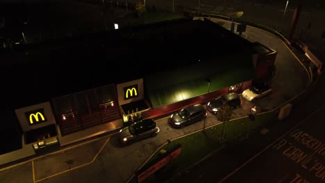 Fliegen-über-Autos,-Die-Bei-Mcdonalds-Fast-Food-Warten,-Fahren-Nachts-Durch-Die-Luftaufnahme