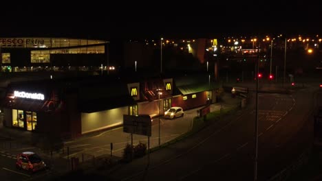 Cola-De-Coches-Fuera-De-La-Comida-Rápida-De-Mcdonalds-En-Coche-Por-La-Noche-En-La-Ciudad-Del-Norte-Del-Reino-Unido-Vista-Aérea-Descendente