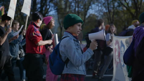 Young-female-activist-holding-megaphone-marching-in-Berlin-economic-inflation-crisis-protest,-Slow-motion