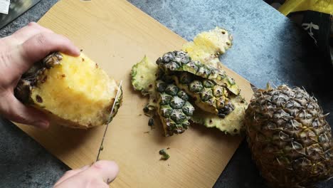 Männliche-Hände-Schneiden-Saftige-Reife-Bio-Ananas-Mit-Scharfem-Messer-Auf-Holzküchen-Schneidebrett