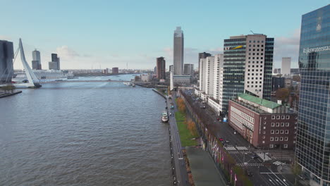 Cruise-Ship-Docked-On-The-Riverside-Near-Erasmus-Bridge-With-Line-Of-Contemporary-Buildings-On-The-Bank-Of-Nieuwe-Maas-In-Rotterdam,-Netherlands