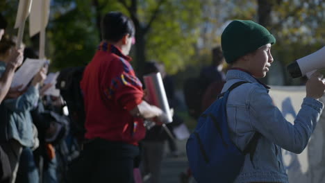 Young-girl-activist-protests-on-street-using-megaphone,-slow-motion,-day