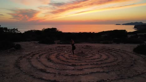 Frau,-Die-Vrksasana-Yoga-Pose-Macht,-Die-In-Der-Mitte-Von-Felsenkreisen-Steht,-Mit-Orangefarbenem-Sonnenuntergang-Am-Horizont-über-Dem-Ozean