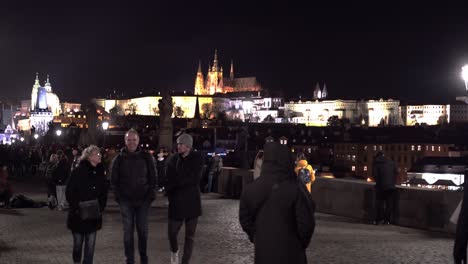 Menschen-Zu-Fuß-Auf-Der-Karlsbrücke-In-Der-Winternacht,-Prager-Burg-Dahinter