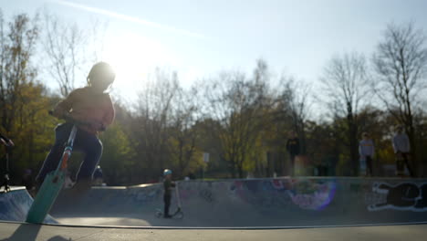 Young-child-jumping-urban-skatepark-bowl-riding-scooter-slow-motion