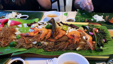 Filipino-food-platter-buffet-with-various-kinds-of-food-like-fish,-vegetables,-prawns,-rice,-and-watermelon-all-in-one