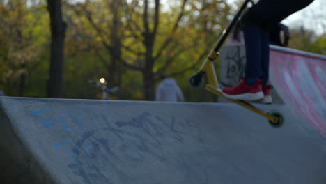 Slomo-close-up-of-young-skater-kid-legs-dropping-in-ramp-at-local-skatepark