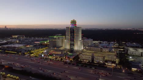 Aerial-view-over-over-traffic-on-the-US-90-and-around-the-Memorial-Hermann-Medical-Center,-dusk-in-Houston,-USA---circling,-drone-shot