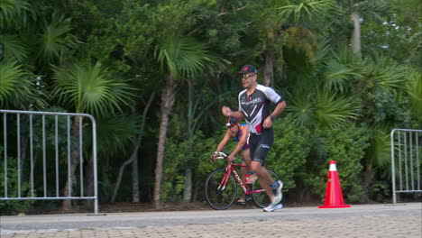 Cámara-Lenta-De-Un-Grupo-De-Atletas-Compitiendo-En-Un-Triatlón-Corriendo-Y-Montando-En-Bicicleta