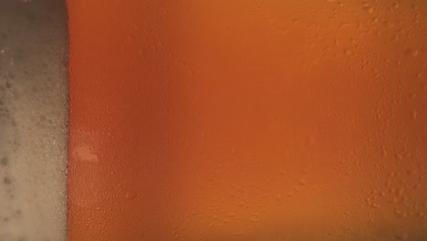 Close-up-vertical-shot-of-golden-pint-of-beet-in-glass,-rotating