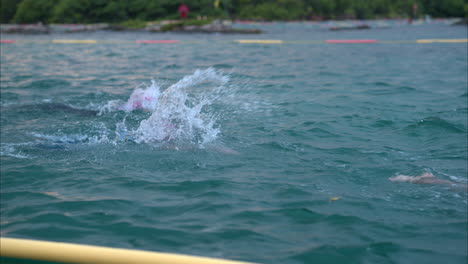 Zeitlupe-Nahaufnahme-Von-Zwei-Schwimmern,-Die-An-Einem-Triathlon-Im-Meer-Mit-Rosa-Mützen-Und-Schutzbrillen-Teilnehmen