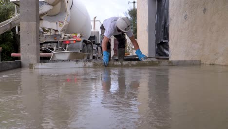 Low-rotating-shot-of-a-worker-using-a-large-bar-to-flatten-out-the-surface-of-the-concrete