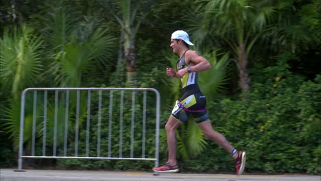 Slow-motion-of-a-male-athlete-running-about-to-finish-a-triathlon-competition-celebrating-cheering-with-his-arm