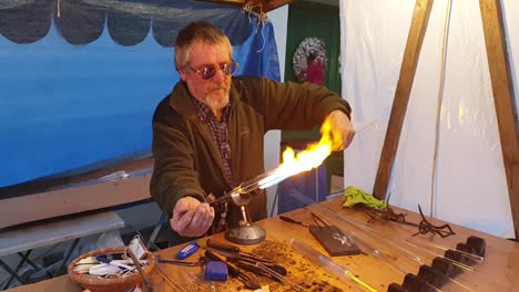 Glassblower-artisan-shaping-the-hot-molten-glass-at-strong-fire-inside-a-workshop