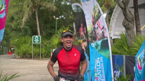 Slow-motion-of-a-male-triathlon-athlete-finishing-the-competition-celebrating-cheering-with-his-arms-up