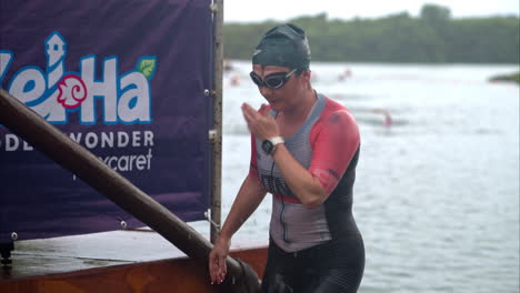 Atleta-Femenina-Que-Termina-La-Etapa-De-Natación-En-Un-Triatlón-Viendo-Su-Tiempo-En-Su-Reloj-Deportivo-Con-Gorra-Y-Gafas