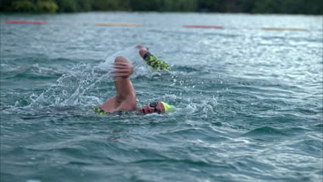 Primer-Plano-En-Cámara-Lenta-De-Dos-Nadadores-Compitiendo-En-Un-Triatlón-En-El-Mar-Con-Gorras-Y-Gafas