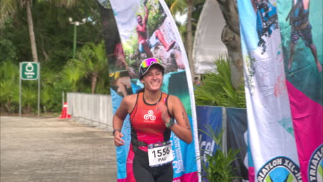 Cámara-Lenta-De-Una-Atleta-De-Triatlón-Femenina-Que-Termina-La-Competencia-Sonriendo-Y-Luciendo-Exhausta