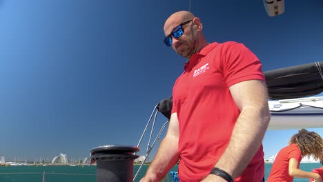 Panning-shot-of-a-captain-holding-onto-a-rope-on-the-boat-to-drop-an-anchor