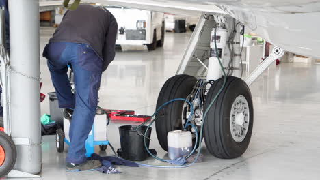 Mechanic-working-on-hydraulic-fluid-system-of-landing-gear