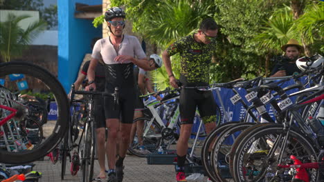 Cámara-Lenta-De-Un-Grupo-De-Atletas-Masculinos-Que-Terminan-La-Etapa-De-Ciclismo-Ingresando-A-La-Zona-De-Transición-En-Un-Triatlón