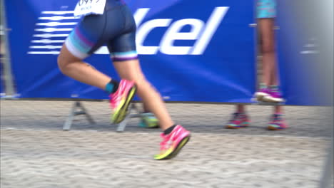 Movimiento-Lento-De-Las-Piernas-De-Un-Atleta-Comenzando-La-Etapa-De-Carrera-En-Un-Triatlón-Dentro-De-La-Zona-De-Transición