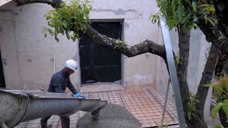 Trabajador-De-La-Construcción-Con-Equipo-De-Seguridad-Empobreciendo-Cemento-En-El-Suelo