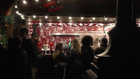 Sillhouute-De-Gente-Caminando-Por-El-Puesto-De-Chocolate-Caliente-En-Los-Mercados-Navideños-De-Trafalgar-Square-En-La-Noche-En-Londres