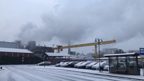 Car-parking-in-front-of-sugar-factory-in-Malbork,-Poland,-smoke-rising-from-chimneys