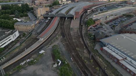 Hochkippen-Der-Drohne-Aus-Der-Luft,-Die-Den-Bahnhof-Von-York-Mit-Dem-Zug-Zeigt,-Der-An-Einem-Sonnigen-Und-Bewölkten-Abend-In-North-Yorkshire,-Großbritannien,-In-Den-Bahnhof-Einfährt