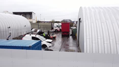 Rising-aerial-view-over-backstreet-city-industrial-truck-yard-mechanics-workplace