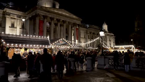 Busy-View-Of-Trafalgar-Square-Christmas-Market-Outside-The-National-Gallery-At-Night-In-London